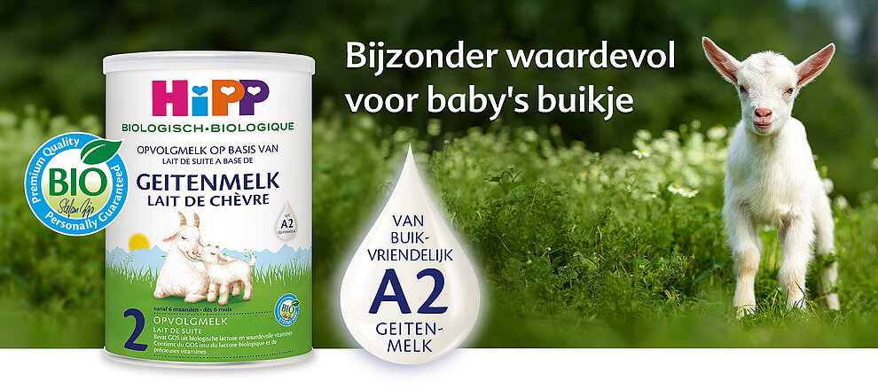 Een babygeitje staat in een groen veld naast een container met biologische geitenmelkpoeder, met een druppel melk met het label "A2-geitenmelk".