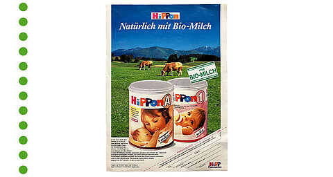 Eine Produktwerbung für "HiPPon"-Babynahrung mit einem malerischen Hintergrund einer grünen Wiese und grasenden Kühen, die die Verwendung von "BIO-MILCH" hervorheben.