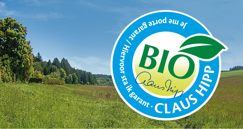 Un paysage verdoyant avec des arbres et de l'herbe est recouvert d'un logo circulaire bleu avec le mot "BIO" en blanc, une feuille verte et le texte "CLAUS HIPP" en blanc.
