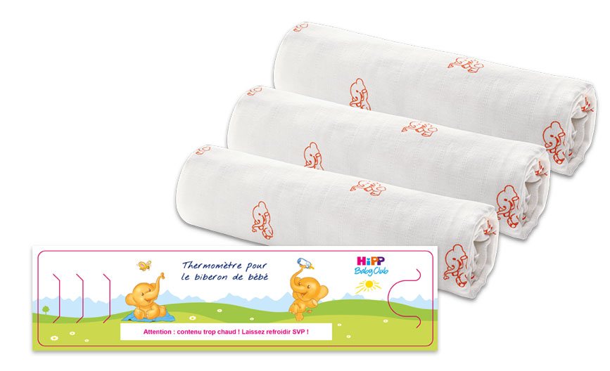 Trois langes blancs avec des motifs d'éléphants rouges sont soigneusement enroulés et une carte rose avec une illustration d'éléphant et de soleil contient des instructions en français.