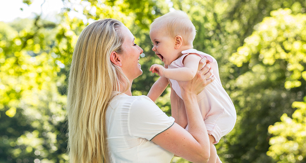 Een vrouw houdt een baby vast in de buitenlucht.