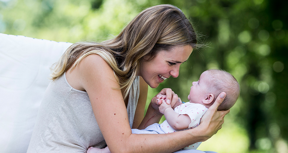 Een vrouw houdt buiten een baby vast.