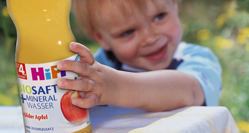 A child is holding a bottle of apple juice.