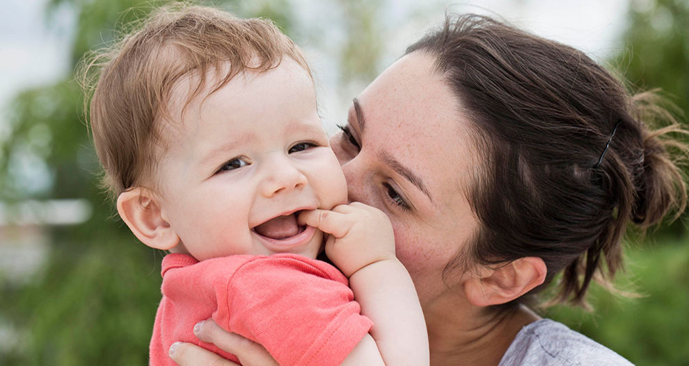 A woman lovingly holds a laughing baby.